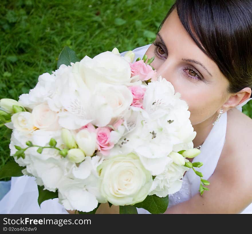 Happy bride with bouquet posing outdoors