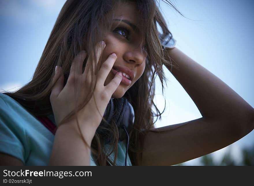 Young beautiful girl with earphones smiling. Outdoor photo.