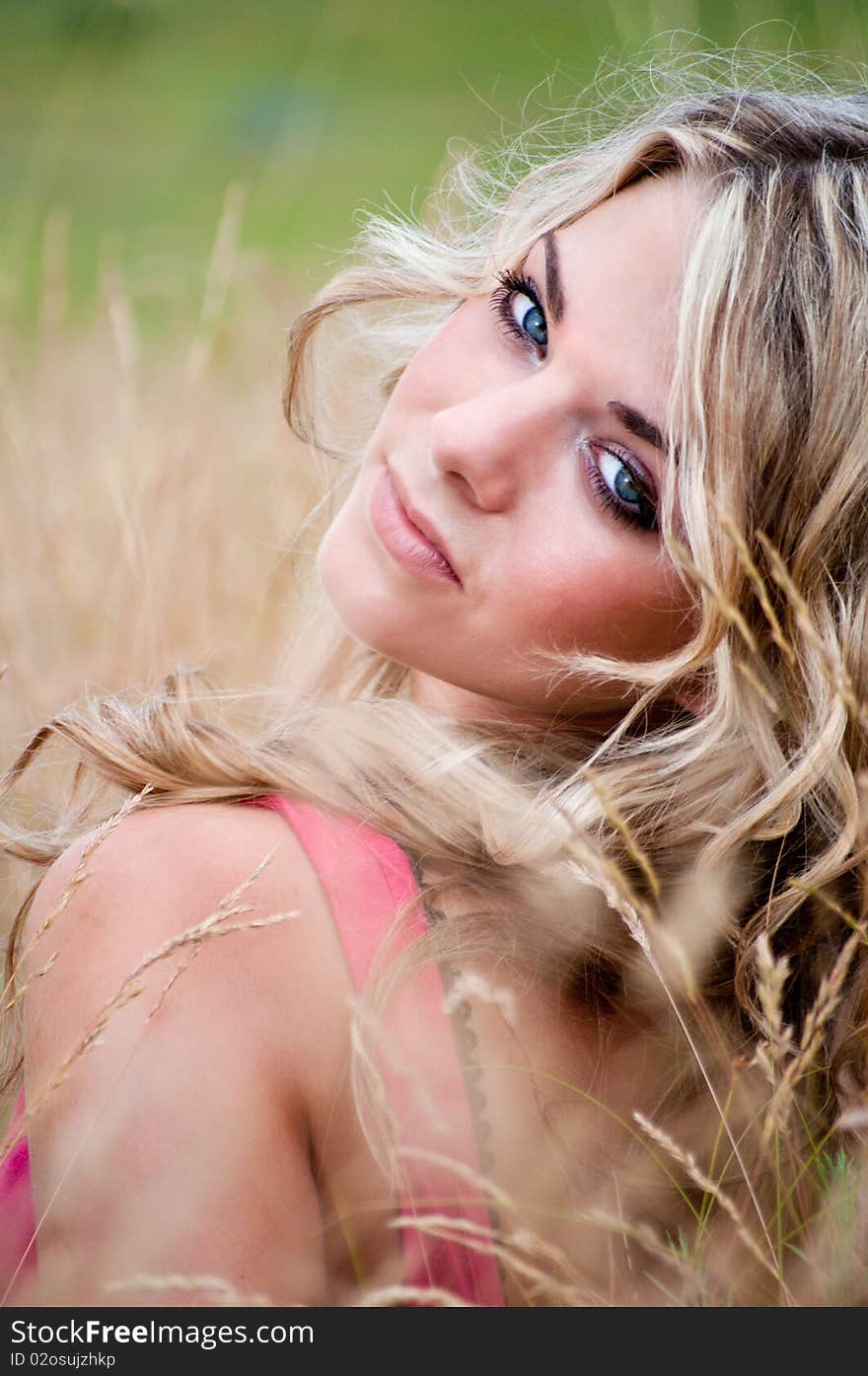 Portrait of a blue-eyed blonde young woman on a meadow background