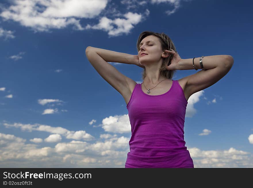 Young female stretching her arms against blue cloudy sky. Young female stretching her arms against blue cloudy sky