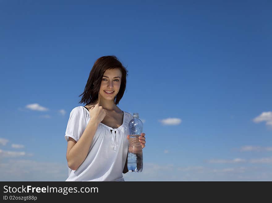 Young female with bootle of water against blue sky