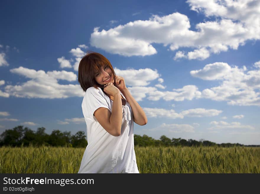 Young female smiling against blue sky and yellow wheat field. Young female smiling against blue sky and yellow wheat field