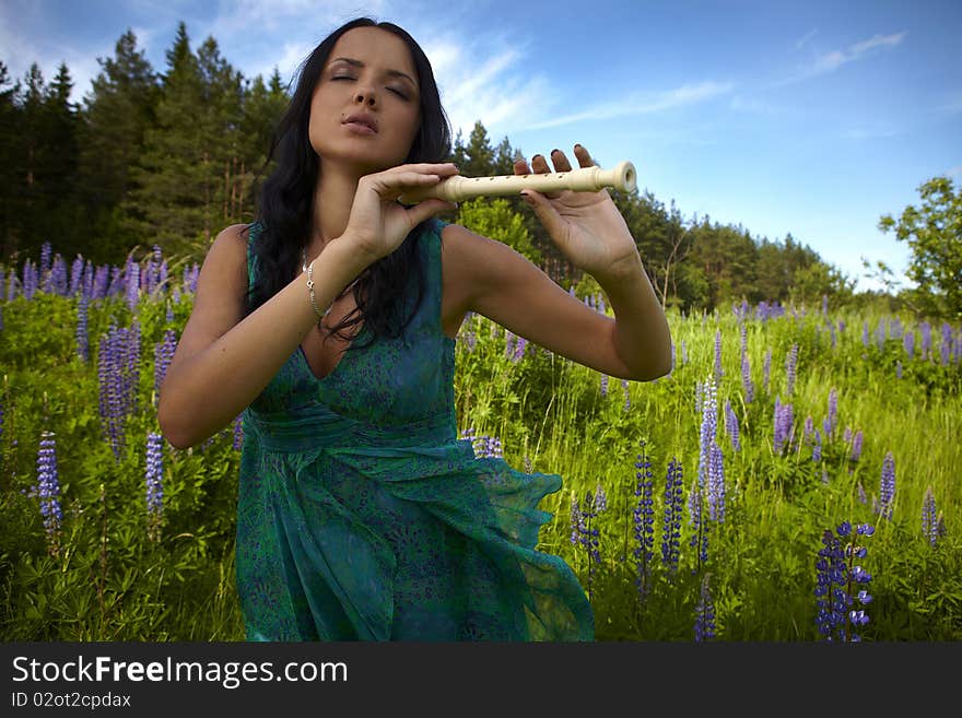 Attractive girl with a flute sitting in a summer field. Photo. Attractive girl with a flute sitting in a summer field. Photo.