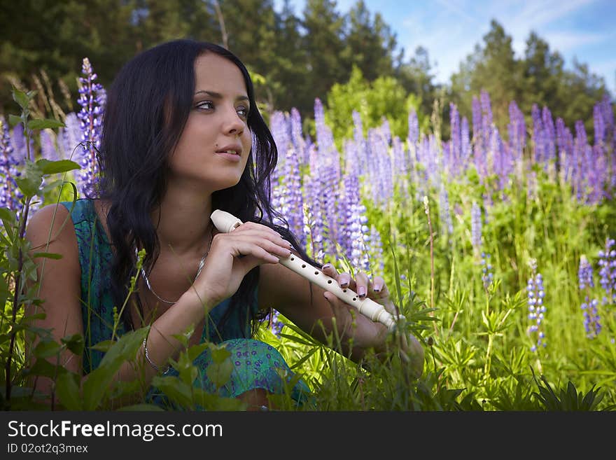 Attractive girl with a flute sitting in a summer field. Photo. Attractive girl with a flute sitting in a summer field. Photo.