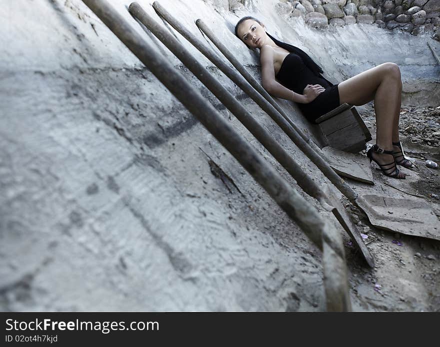 Sexual girl in black dress inside stone quarry among old shovels. Photo.