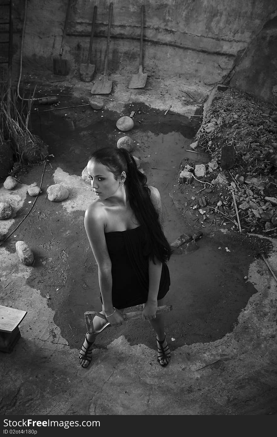 Sexual girl in black dress inside stone quarry among old shovels. Photo.