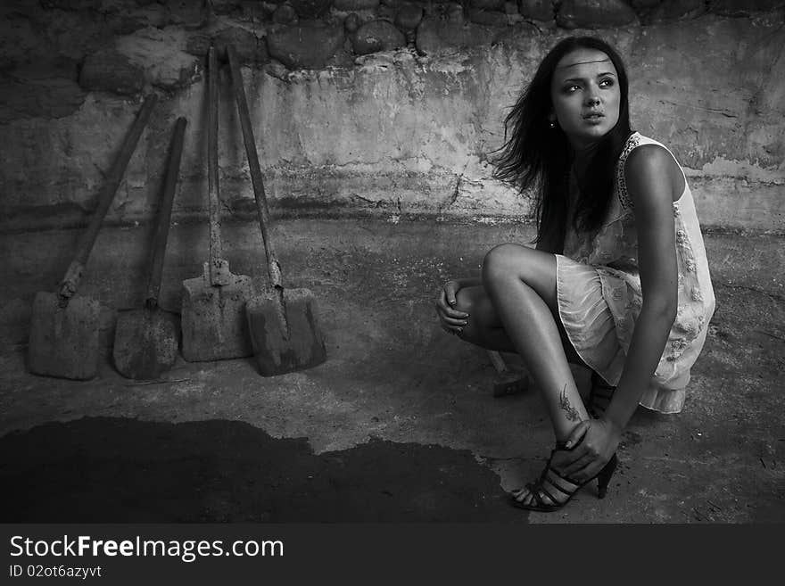 Sexual girl in black dress inside stone quarry among old shovels. Photo.