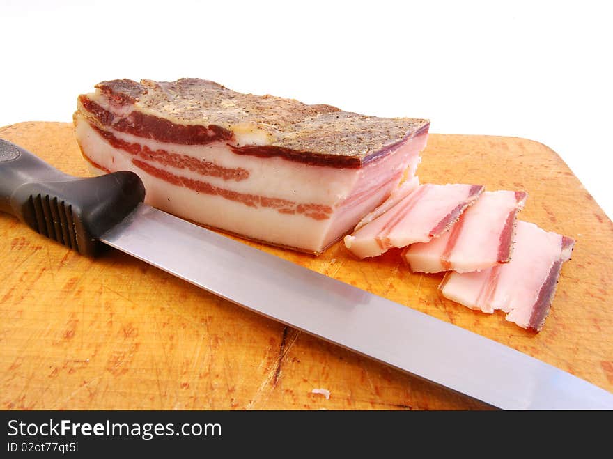 Knife with slices of bacon on a chopping board