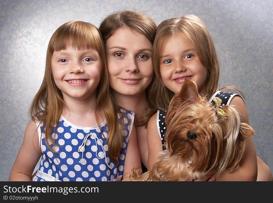 Young mother and two little sisters with Yorkshire terrier over light defocused background. Young mother and two little sisters with Yorkshire terrier over light defocused background