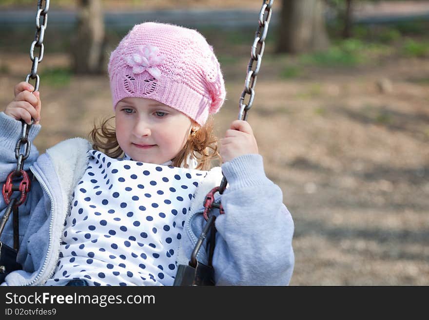 Little girl enjoying the swing in a spring day in the park. Little girl enjoying the swing in a spring day in the park.