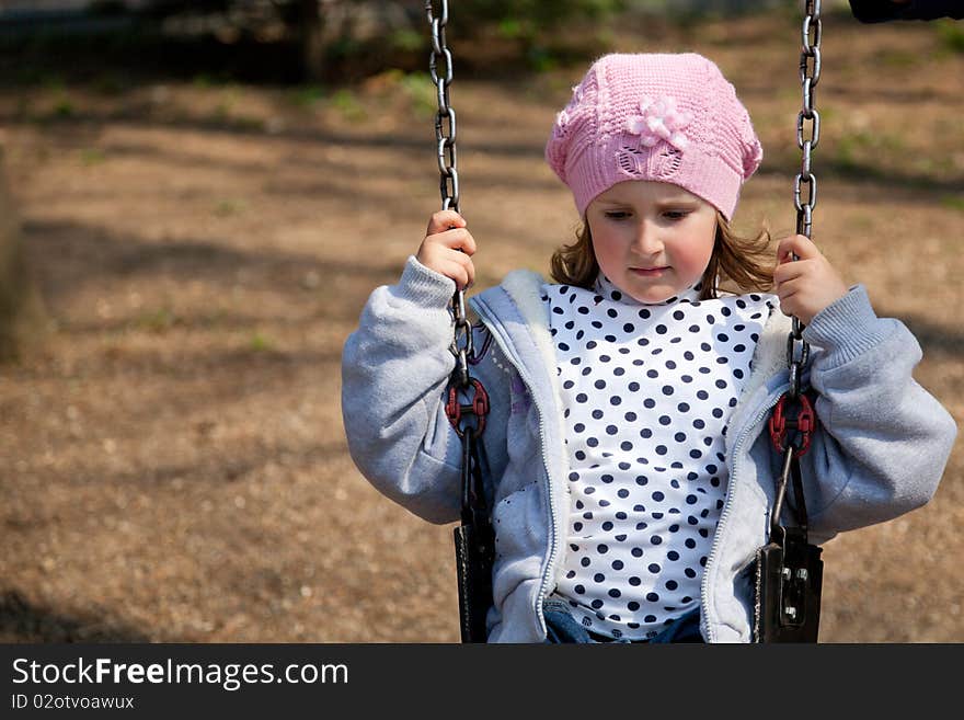 Little girl enjoying the swing in a spring day in the park. Little girl enjoying the swing in a spring day in the park.