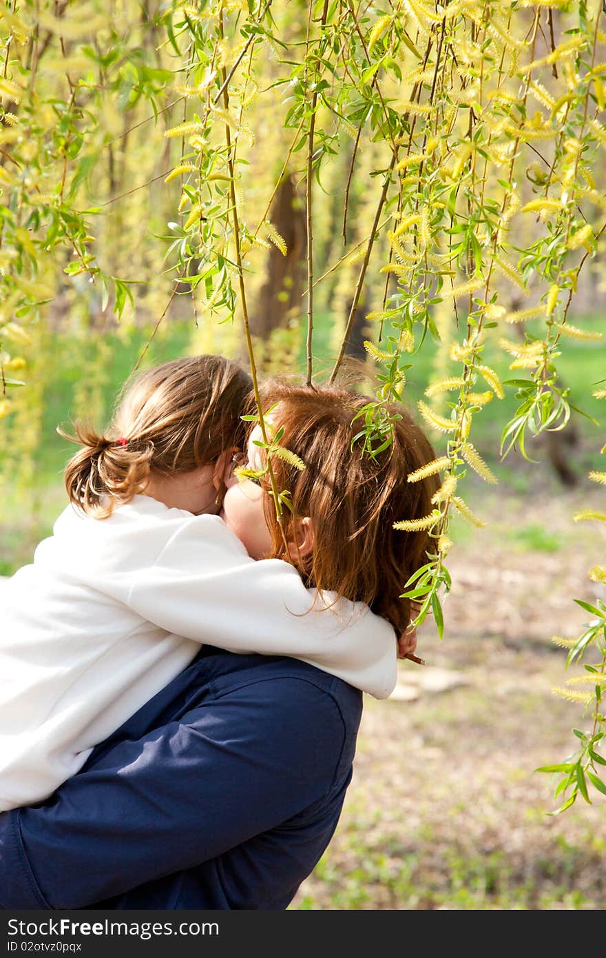 Mother hugging her daughter in the park in spring