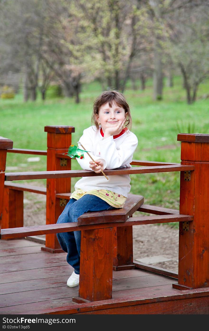 Little girl sitting in the park in spring with a happy expression. Little girl sitting in the park in spring with a happy expression.