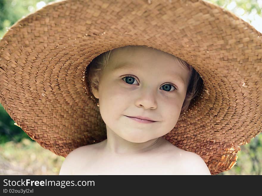 Little cheerful girl in big old straw hat