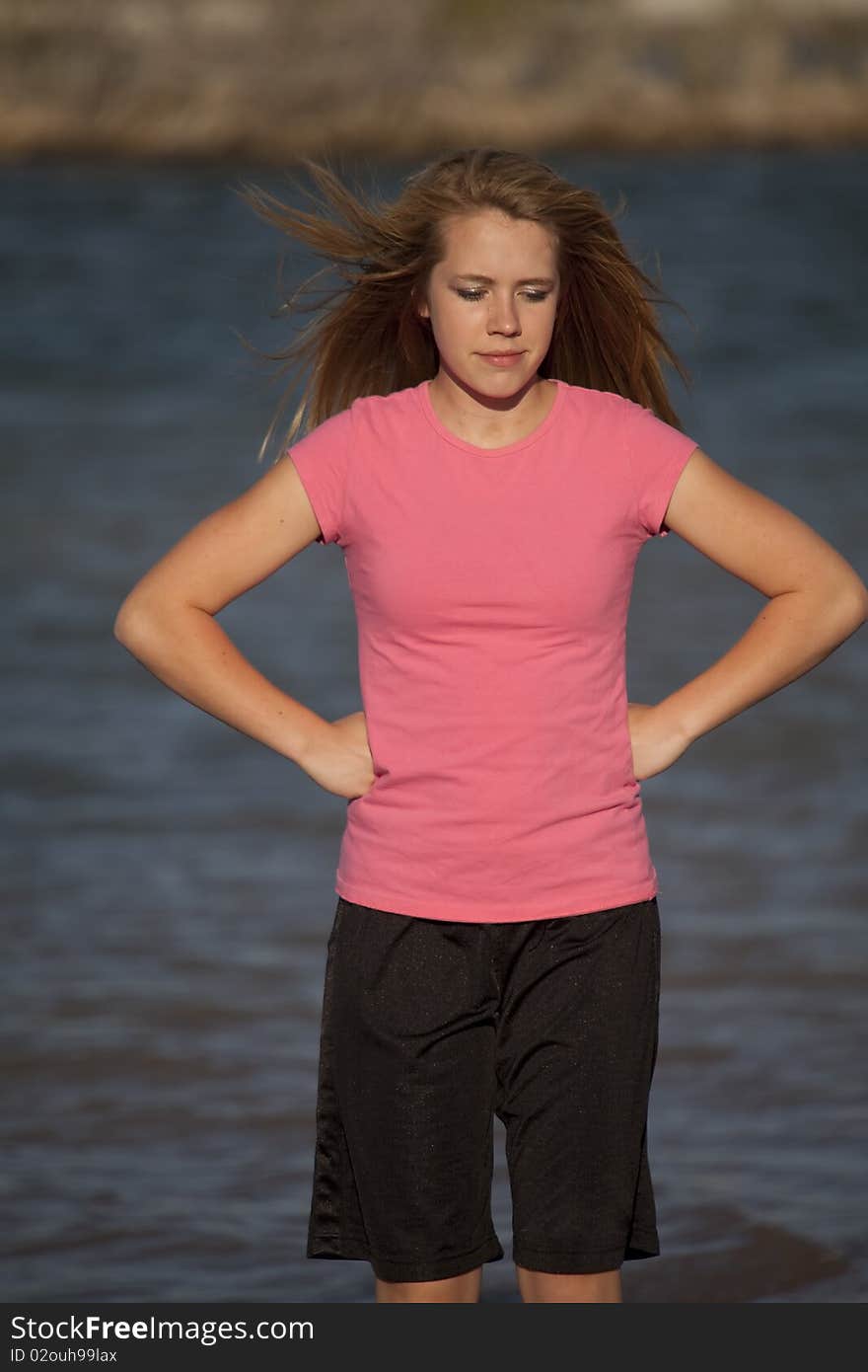 A girl standing in the water thinking.  Hair blowing in the wind. A girl standing in the water thinking.  Hair blowing in the wind.