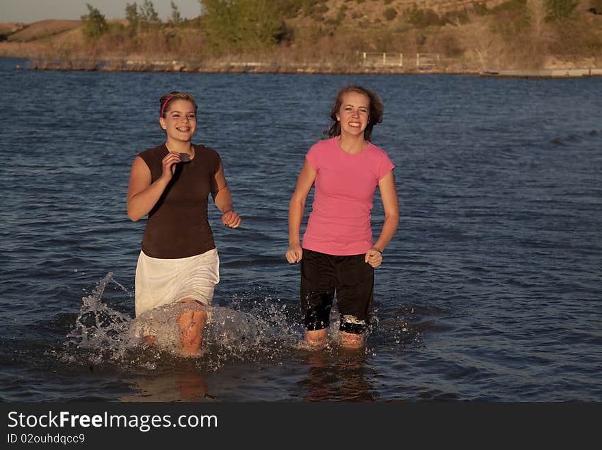 Two girls racing in the water and smiling. Two girls racing in the water and smiling.