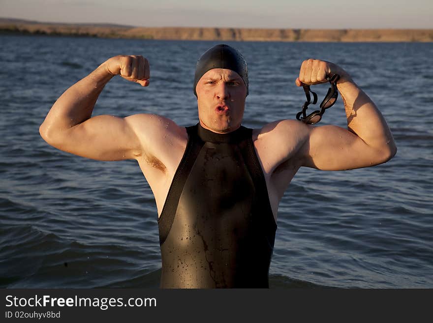 A man standing in the water showing off his muscles. A man standing in the water showing off his muscles.