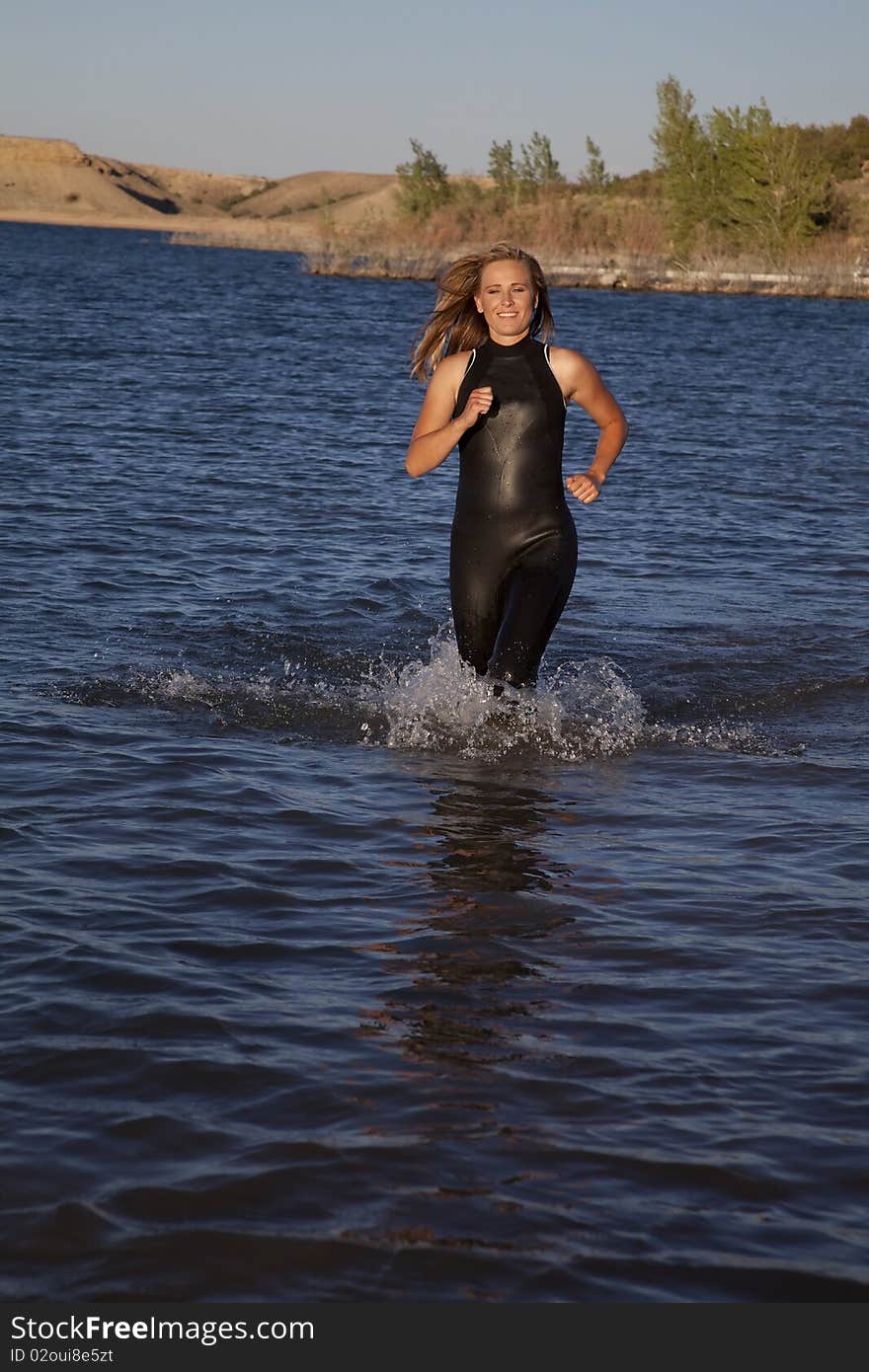 A woman in her wet suit running in the water getting ready to dive in. A woman in her wet suit running in the water getting ready to dive in.