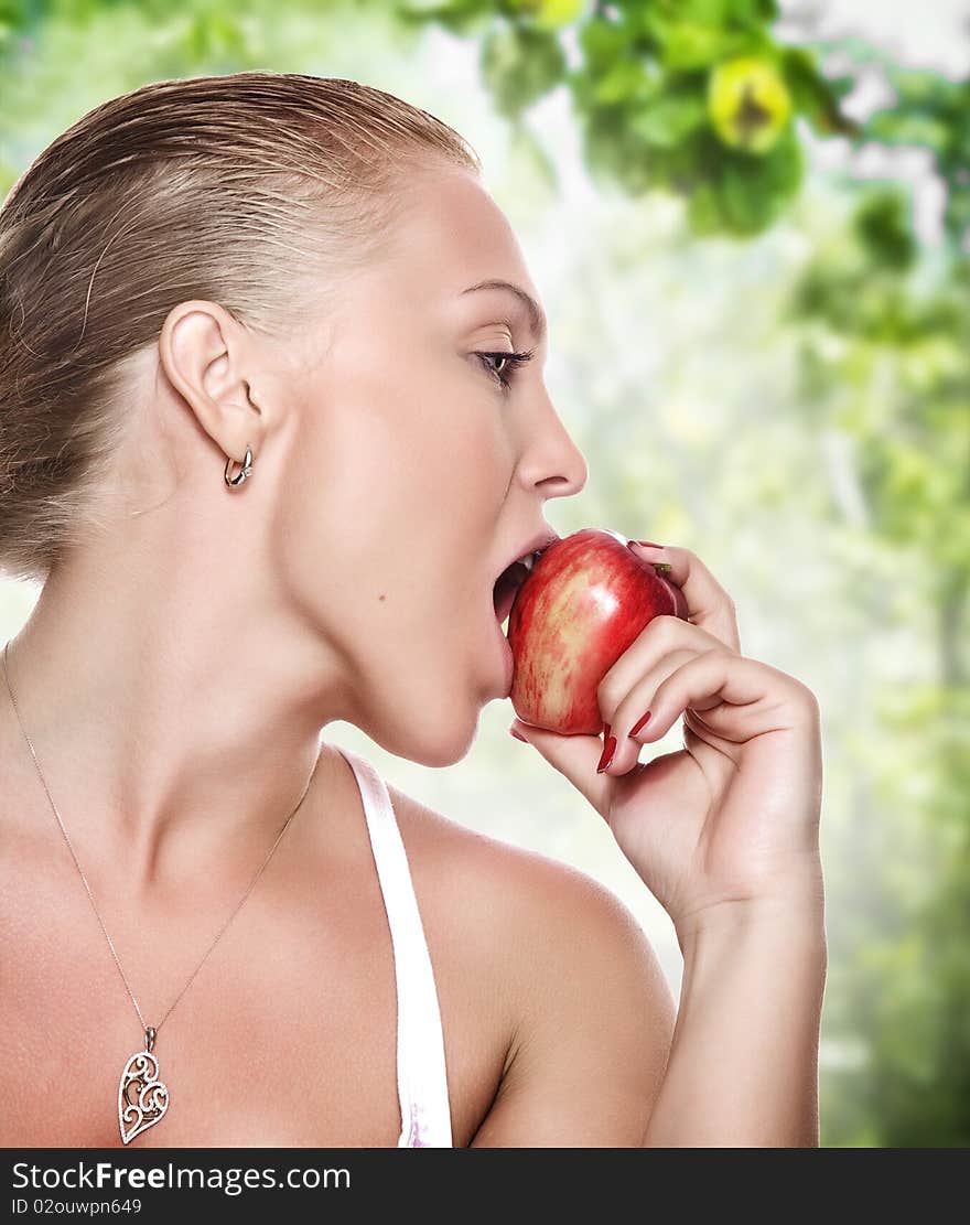 Portrait of young beautiful woman biting apple on blue back. Portrait of young beautiful woman biting apple on blue back