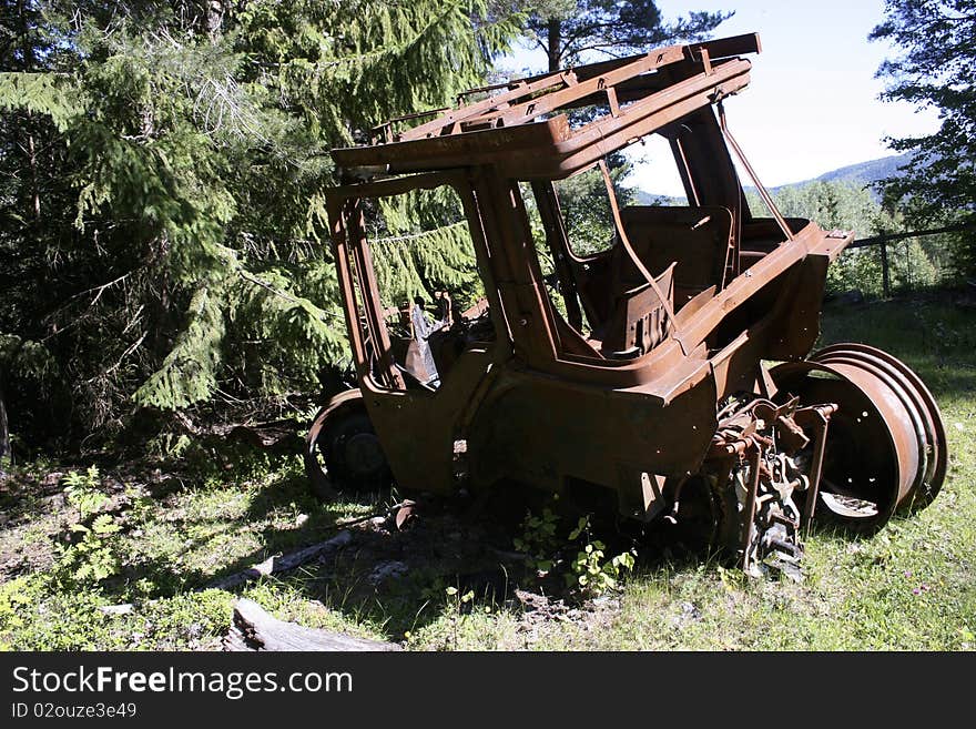 An abandoned old and rusty wreck of a tractor in a forest. An abandoned old and rusty wreck of a tractor in a forest