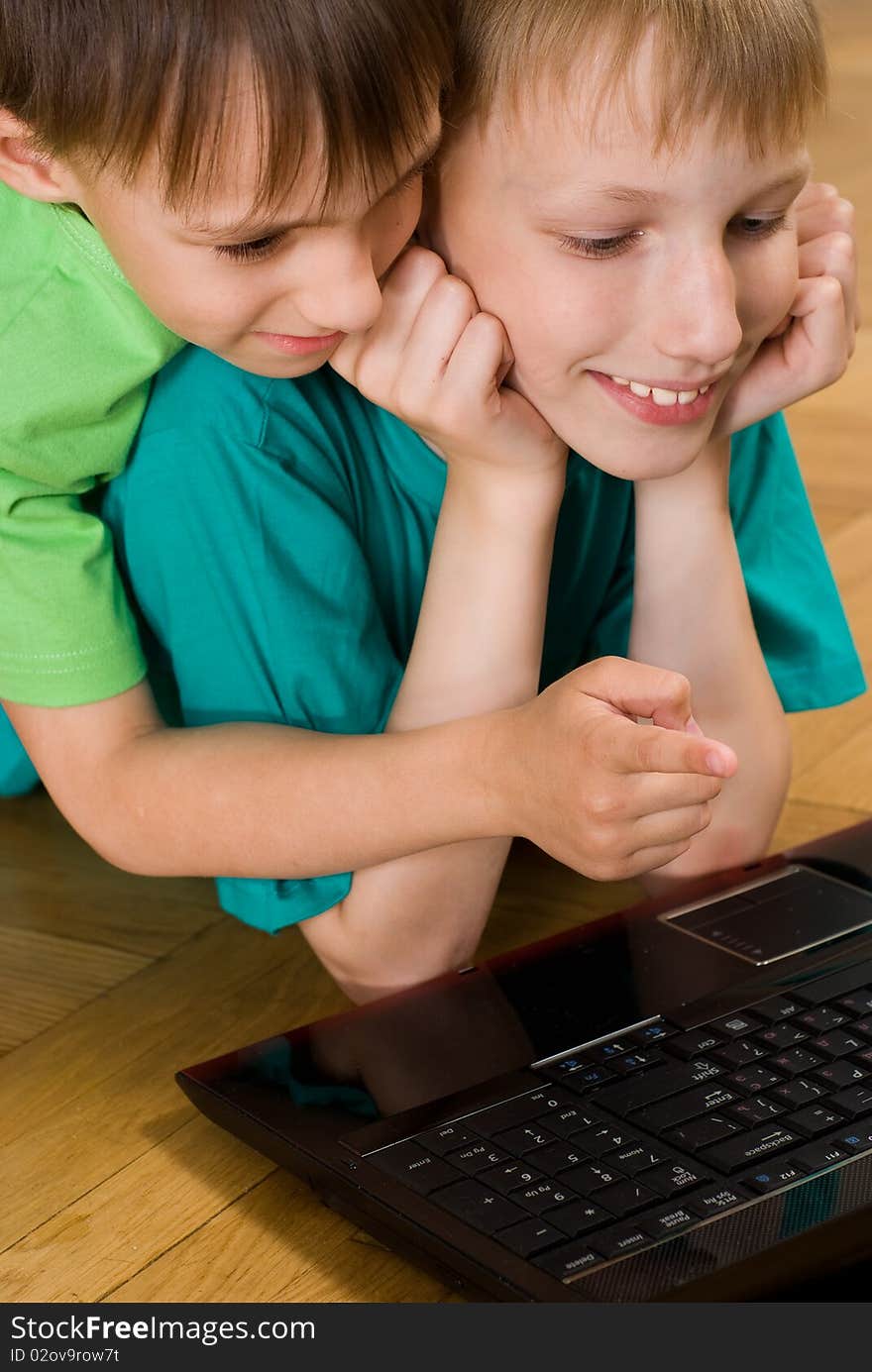 Two little brothers lie with laptop