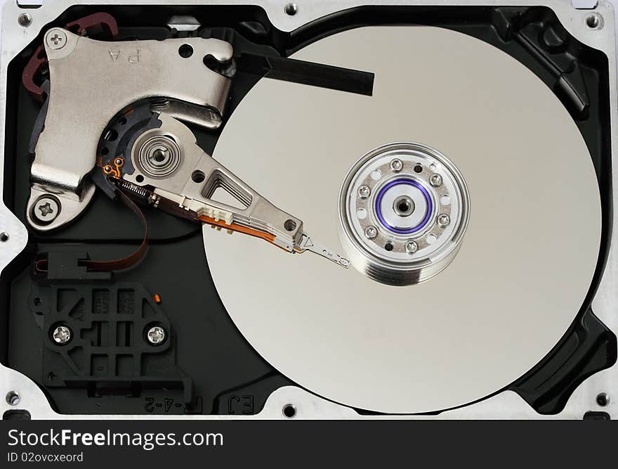 Hard disk. The cover is unclosed. The head reading information from a surface of a hard disk.