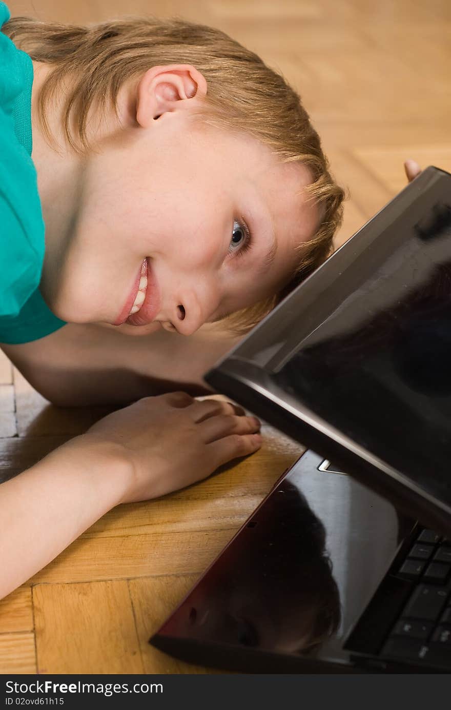 Boy on the floor peering into a laptop. Boy on the floor peering into a laptop