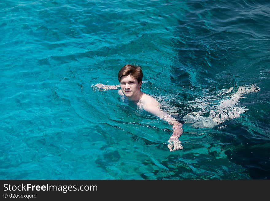 Young man swims in the sea. Swimming