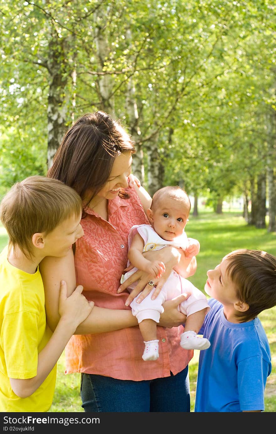 Woman  with  sons and daughter on a background of trees. Woman  with  sons and daughter on a background of trees