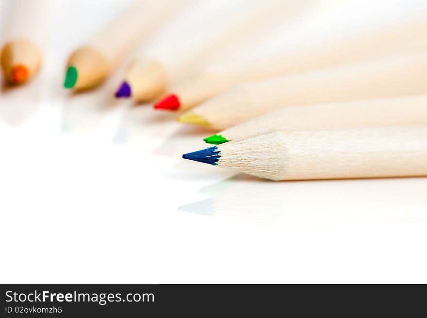 Many colored pencils in row over white background