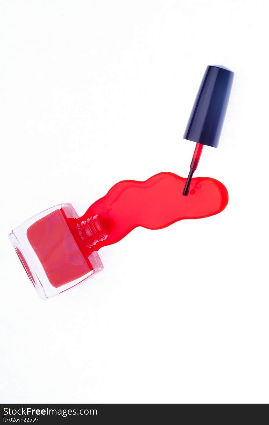 Red pink nail polish spilled on white background, with brush