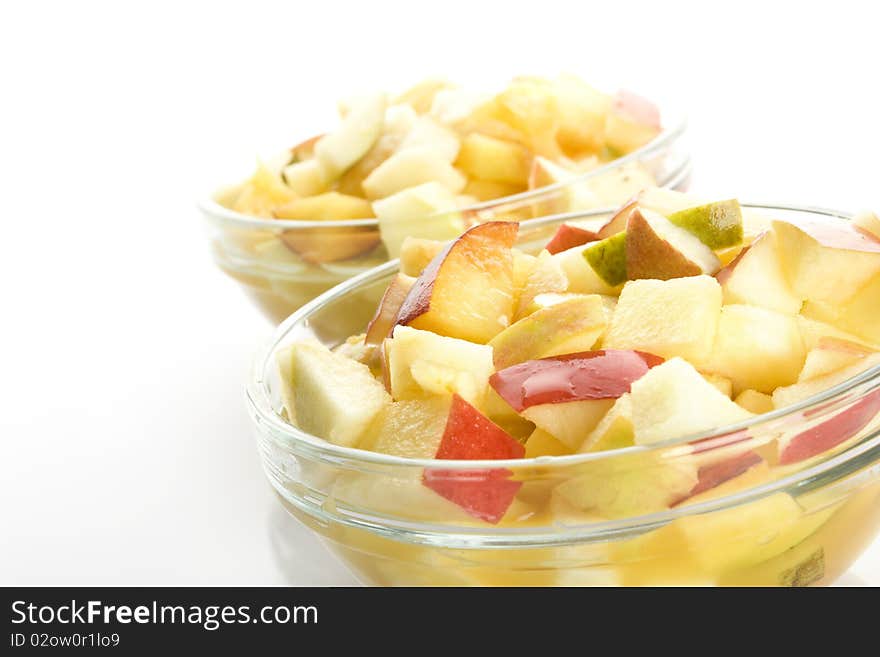 Fruit salad with apples, oranges, peaches, pears and orange juice. Decomposed in two glass plates. Isolated on white background