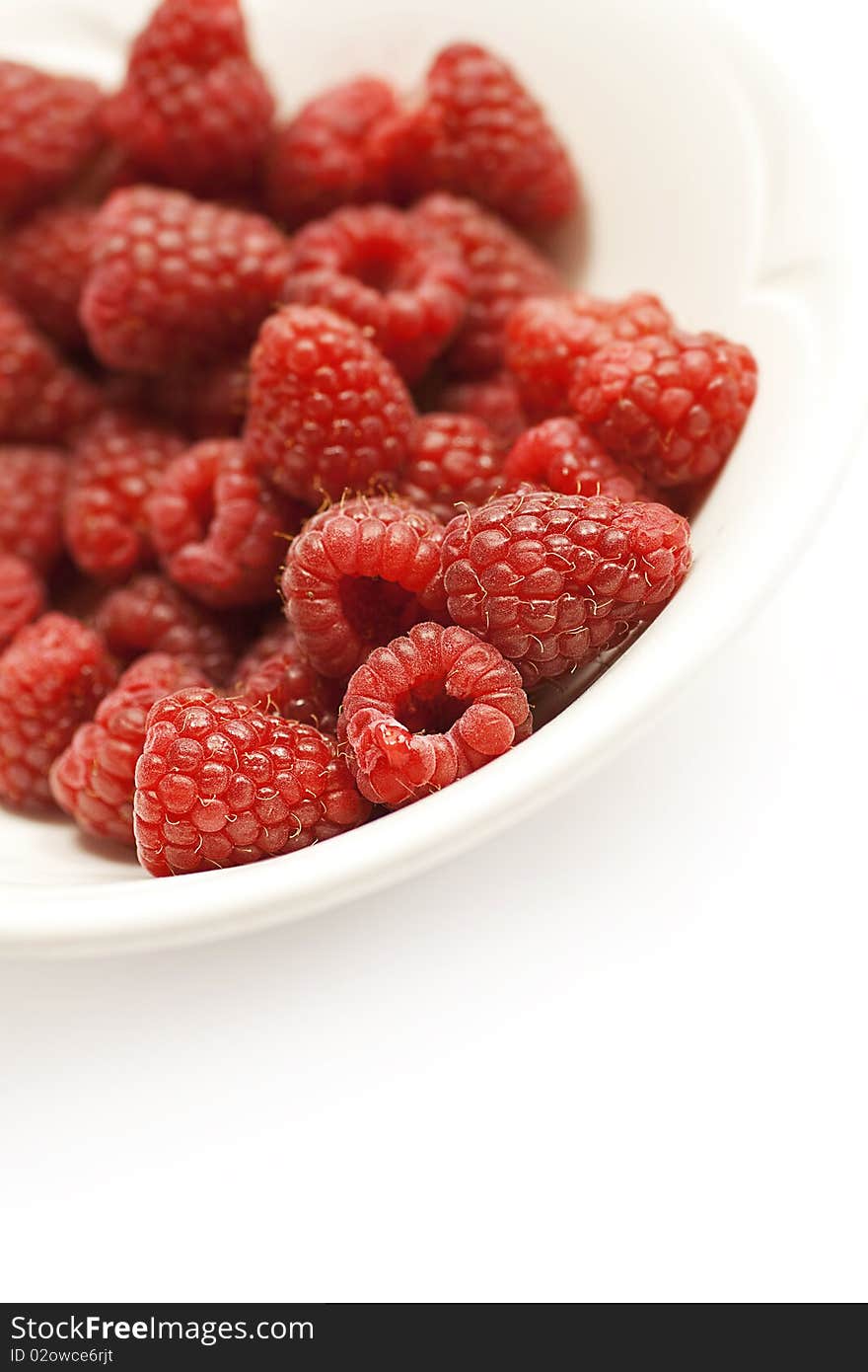 Raspberries in a bowl against white background with plenty of copy space. Healthy eating concept. Raspberries in a bowl against white background with plenty of copy space. Healthy eating concept.