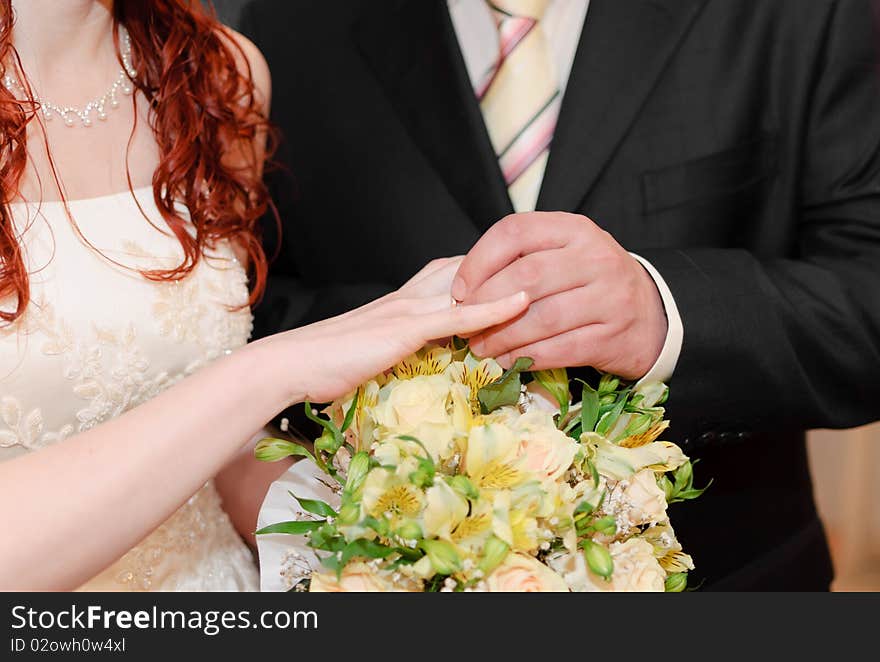 Groom putting on a wedding ring on his bride's finger. Groom putting on a wedding ring on his bride's finger