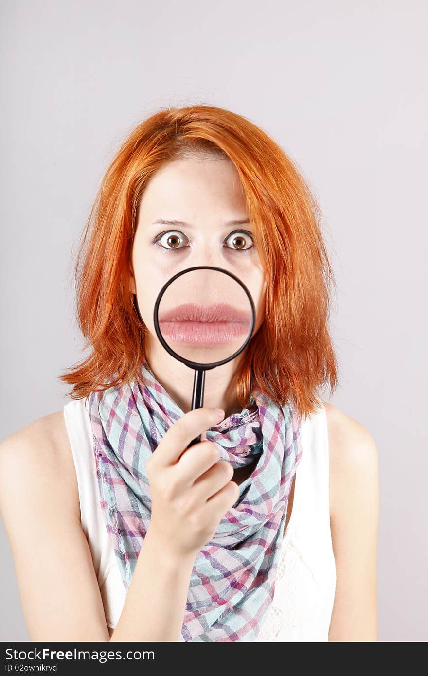 Beautiful red-haired girl with loupe zooming her mouth.