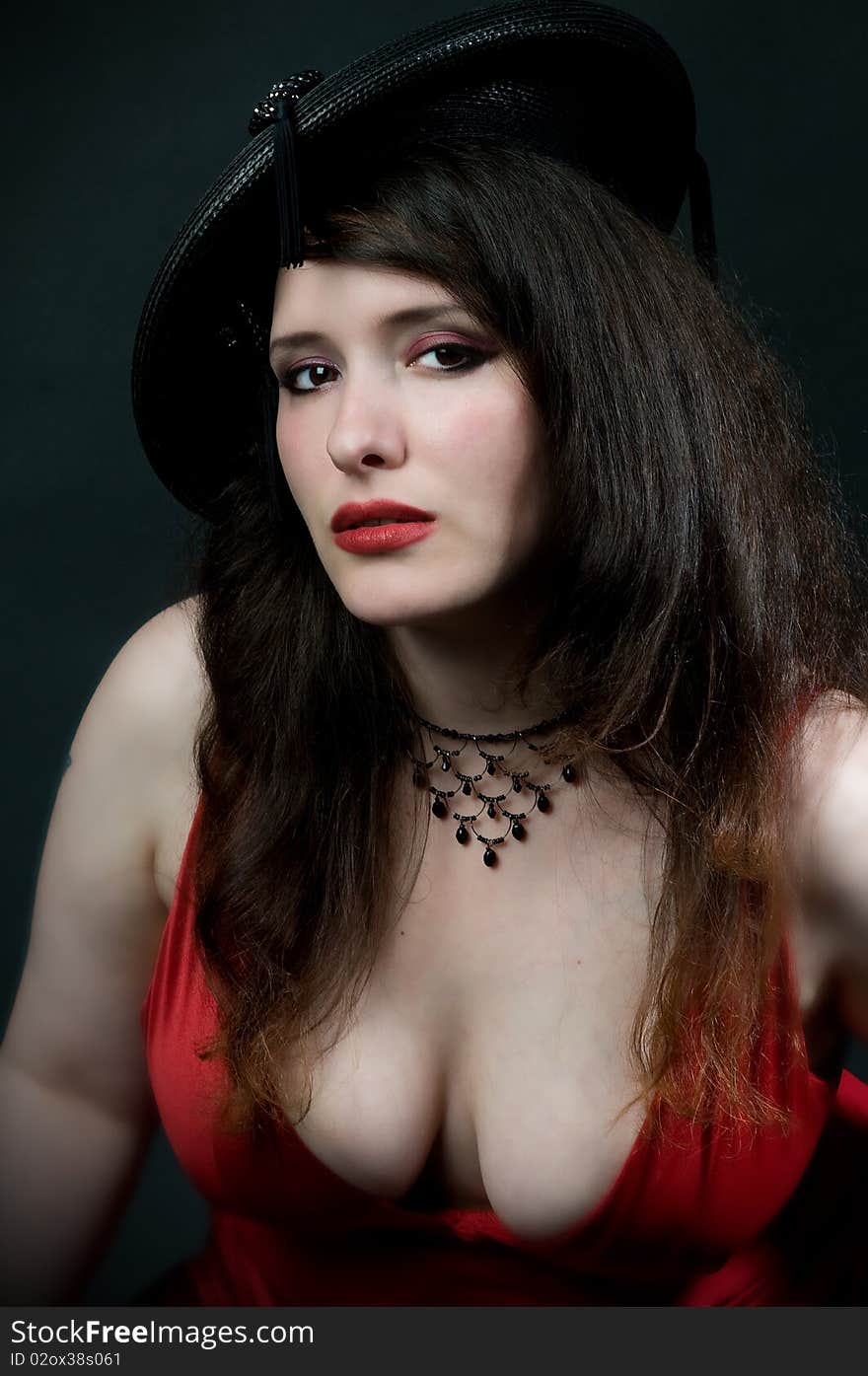 busty woman wearing vintage hat with tassles and low cut red dress. busty woman wearing vintage hat with tassles and low cut red dress