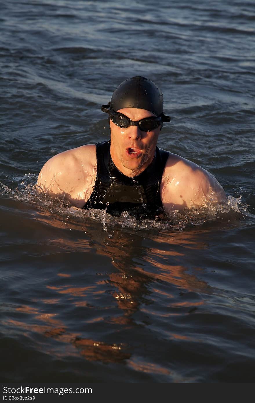 A man in a wet suit swimming. A man in a wet suit swimming.