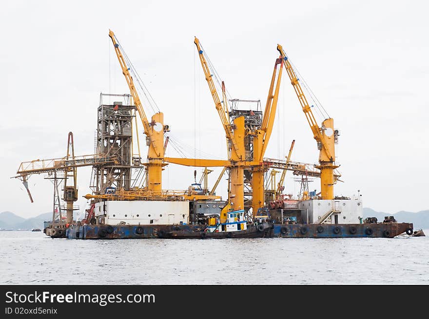 Floating industrial harbour built on barges with a tugboat moored alongside.