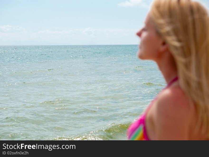 Blonde woman near sea. Focus on water