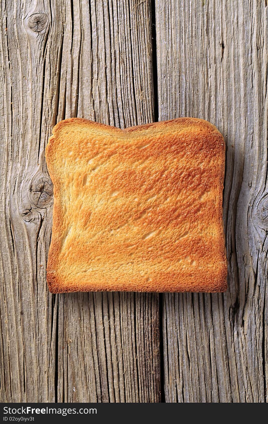 Slice of toasted bread on rough wood