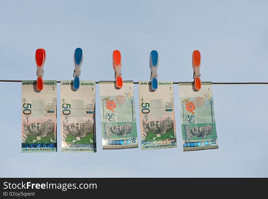 Five drying ringgit bills on a line