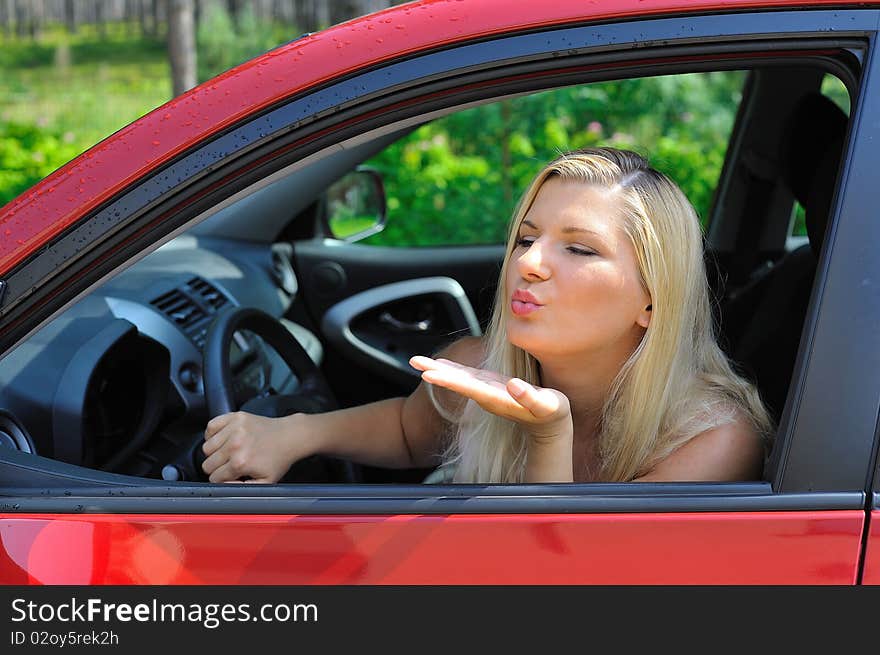 Beautiful woman driver in red shiny car outdoors smiling