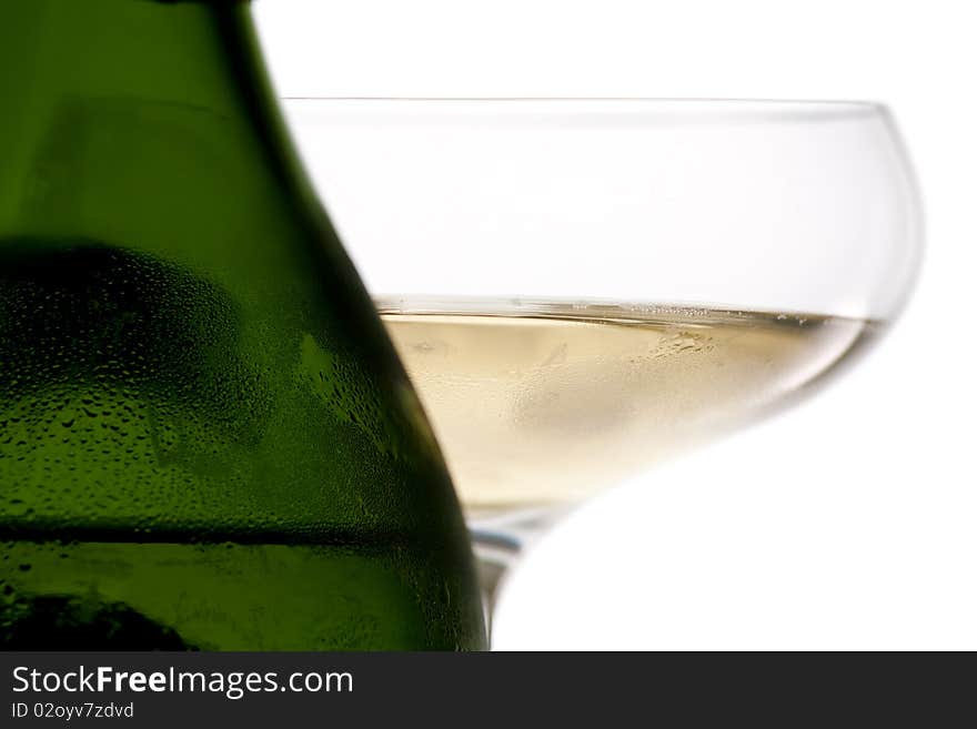 A macro shot of a condensation covered green champagne bottle and a glass of champagne. A macro shot of a condensation covered green champagne bottle and a glass of champagne.
