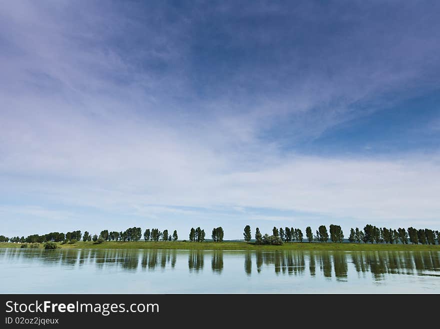 Trees reflections in the river with a big blue sky. Trees reflections in the river with a big blue sky