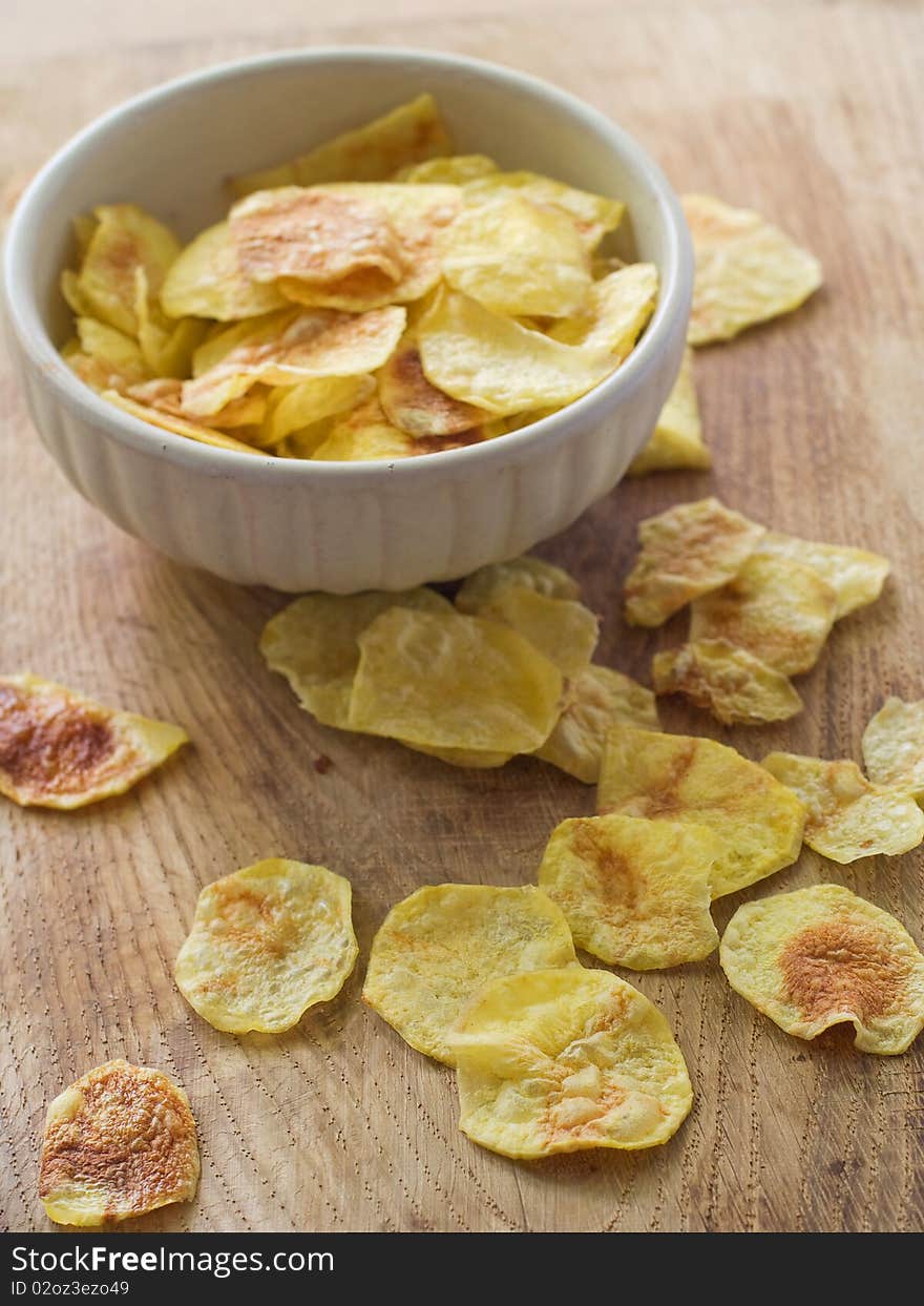 Potato chips in a bowl and scattered on a table