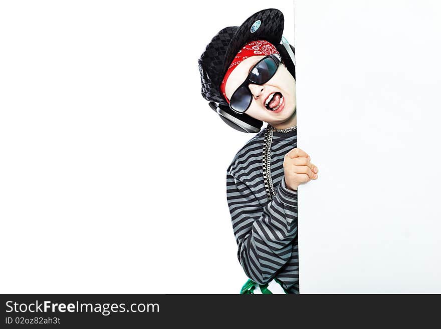 Shot of a trendy teenager listening to music in headphones and holding white board. Isolated over white background. Shot of a trendy teenager listening to music in headphones and holding white board. Isolated over white background.