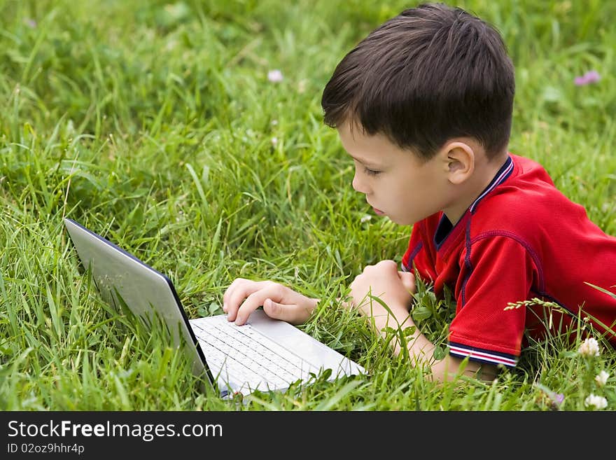 Small boy using notebook outdoor on grass