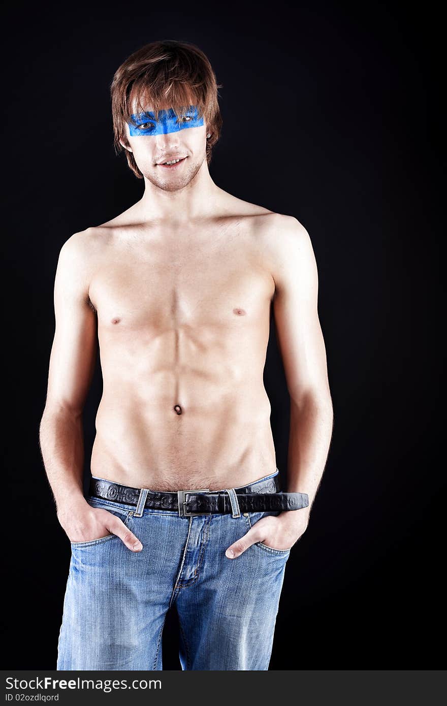 Shot of a posing young man with painted eyes. Over black background. Shot of a posing young man with painted eyes. Over black background.