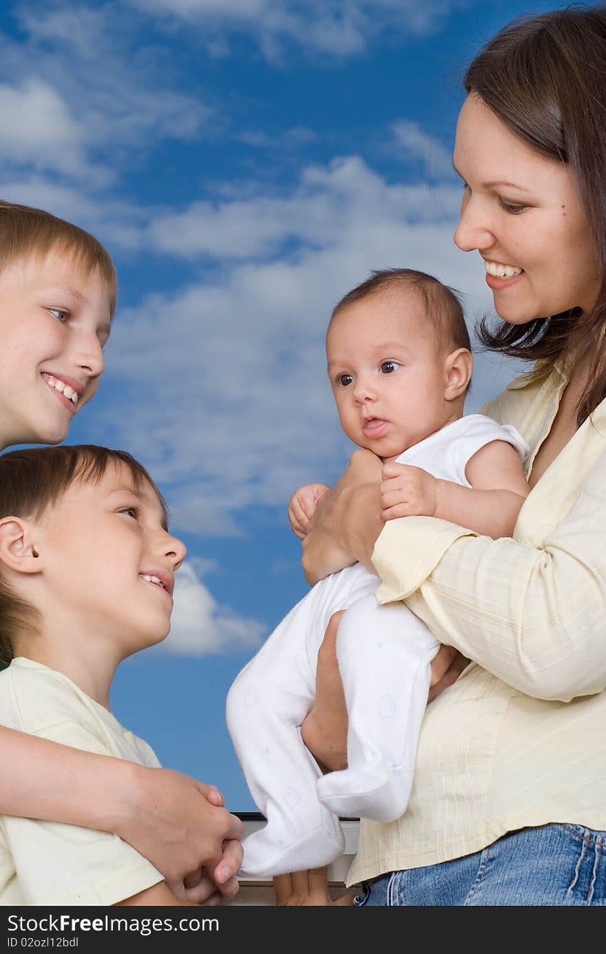 Young mother with three children at the background of the sky