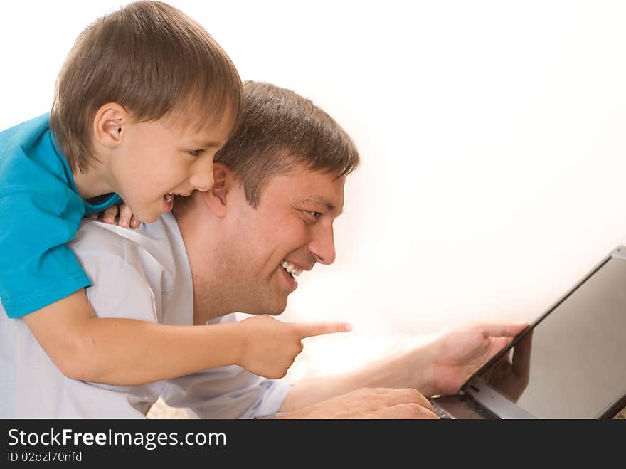 Happy father and son lying with laptop